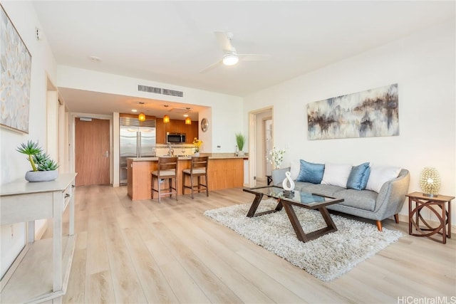 living room with ceiling fan and light hardwood / wood-style flooring