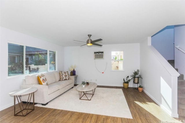 living room featuring dark wood-type flooring, a wall unit AC, and ceiling fan