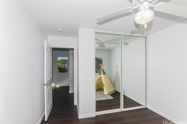 unfurnished bedroom featuring dark hardwood / wood-style flooring, ceiling fan, and a closet