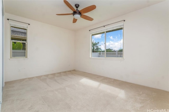 spare room featuring light colored carpet, plenty of natural light, and ceiling fan