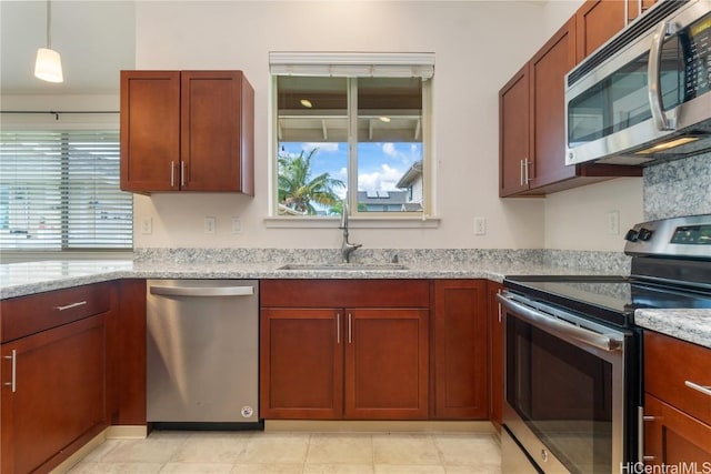 kitchen with pendant lighting, sink, light stone countertops, and stainless steel appliances