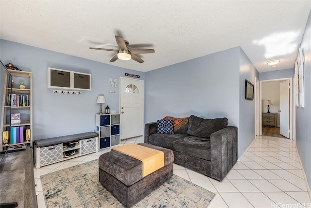 living area with a textured ceiling, light tile patterned flooring, and a ceiling fan