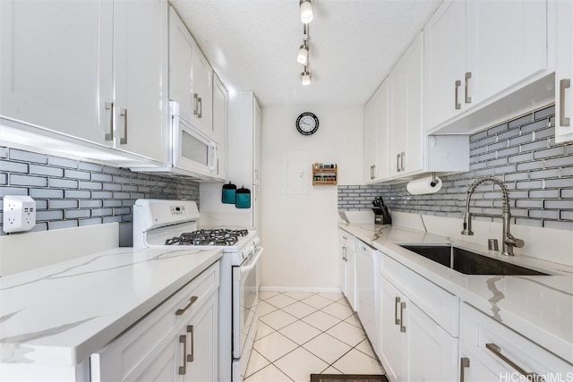 kitchen featuring light tile patterned flooring, sink, white cabinets, light stone counters, and white appliances