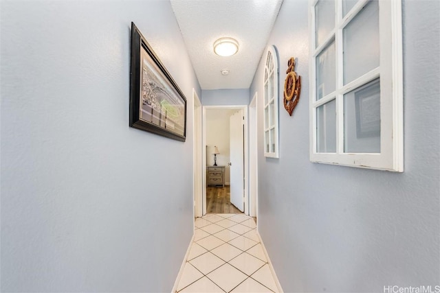 corridor with a textured ceiling and light tile patterned floors