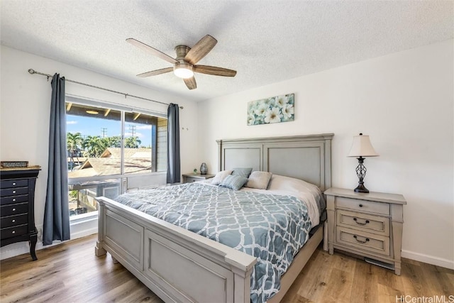 bedroom with ceiling fan, access to exterior, light hardwood / wood-style floors, and a textured ceiling