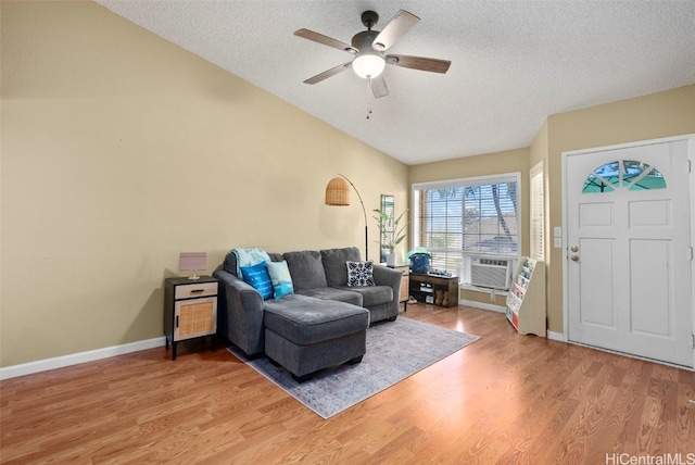 living room featuring lofted ceiling, cooling unit, ceiling fan, light wood-type flooring, and a textured ceiling