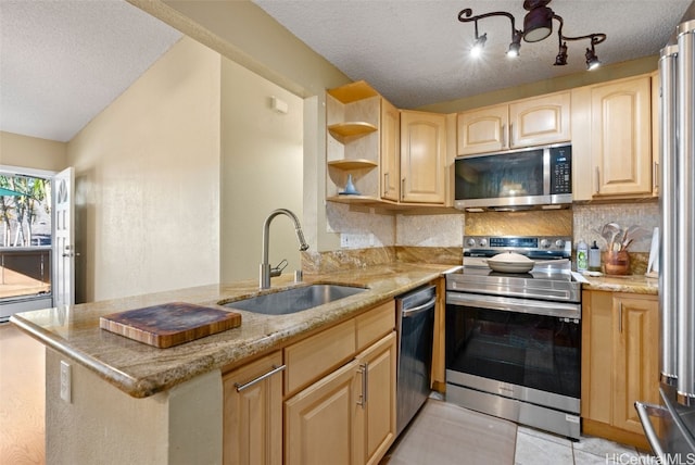 kitchen featuring a peninsula, stainless steel appliances, a sink, and light brown cabinetry