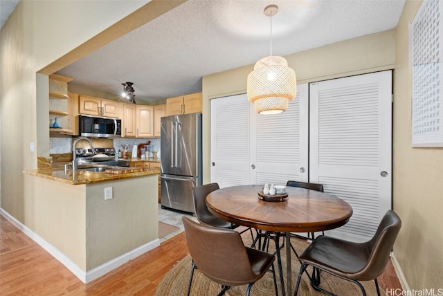 dining space featuring a textured ceiling and light wood-type flooring