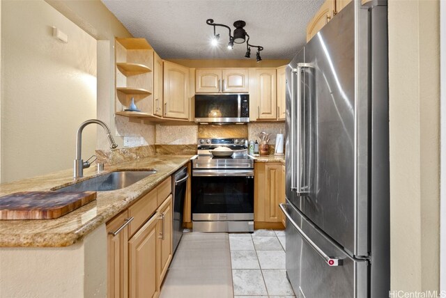 kitchen featuring light brown cabinets, sink, light tile patterned floors, a textured ceiling, and appliances with stainless steel finishes