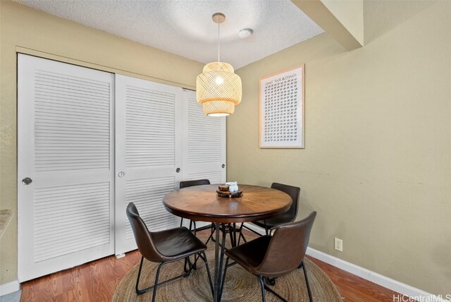 dining space featuring wood-type flooring and a textured ceiling