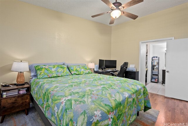 bedroom with ceiling fan, wood-type flooring, and a textured ceiling