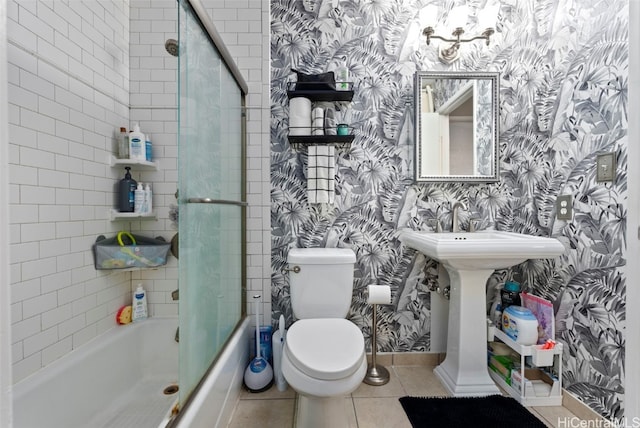 bathroom featuring tile patterned flooring, toilet, and bath / shower combo with glass door