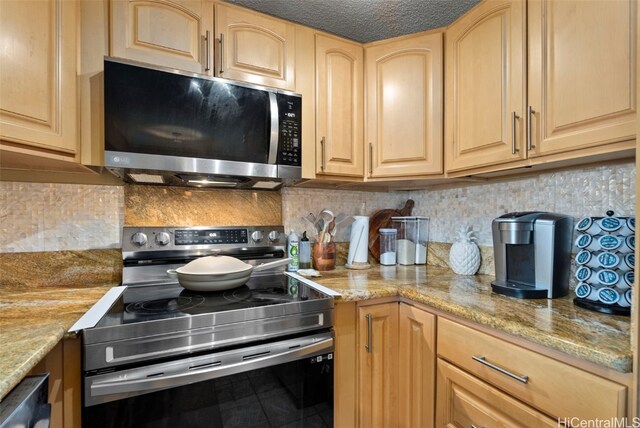 kitchen with decorative backsplash, light brown cabinets, light stone countertops, and appliances with stainless steel finishes