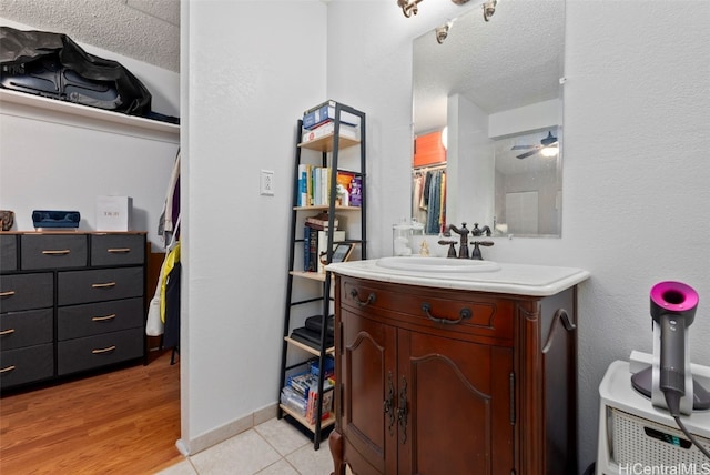 bathroom with a textured ceiling, wood finished floors, vanity, and baseboards