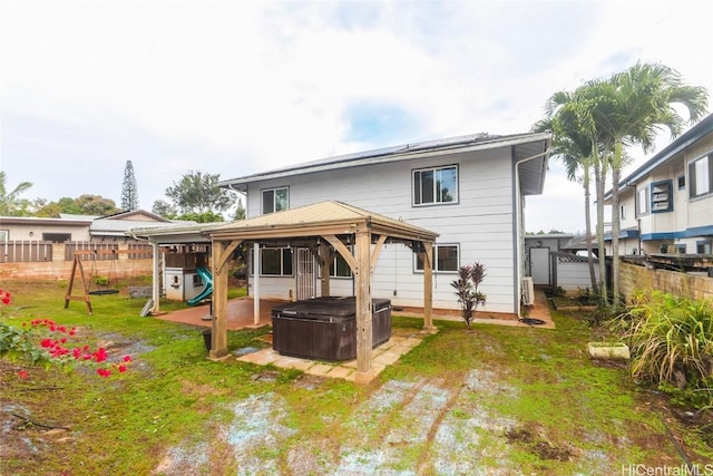 back of house featuring a gazebo, a playground, and a hot tub