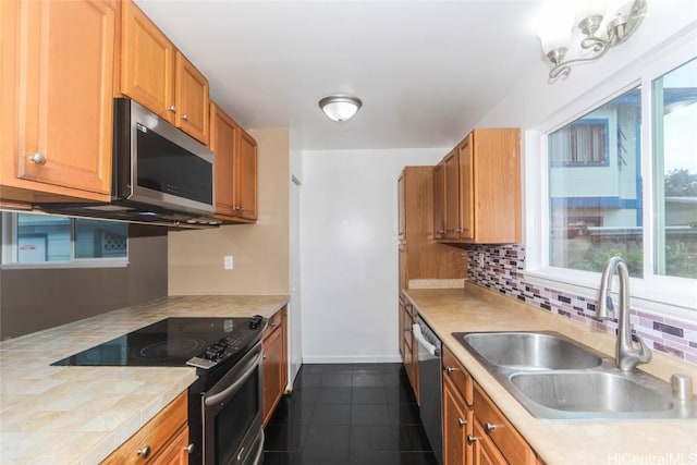 kitchen with appliances with stainless steel finishes, backsplash, dark tile patterned flooring, and sink