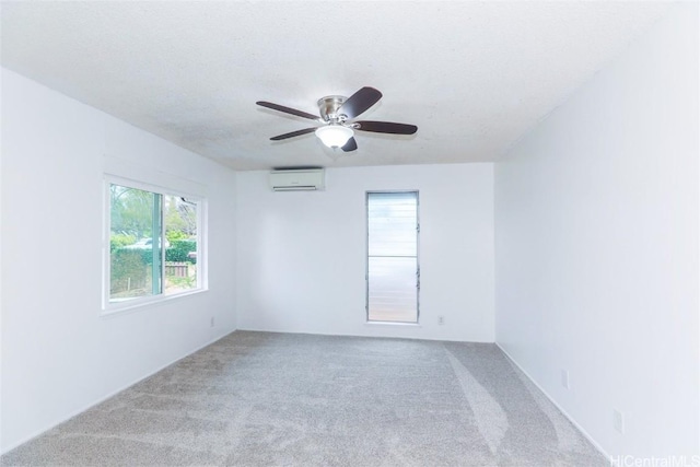 unfurnished room with a wall mounted AC, ceiling fan, plenty of natural light, and carpet floors