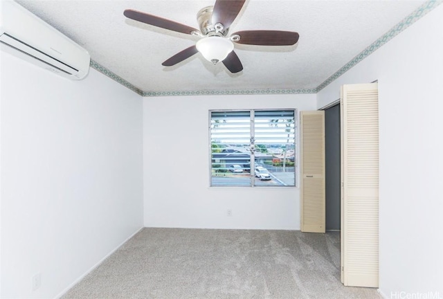 carpeted empty room featuring an AC wall unit, ceiling fan, and a textured ceiling