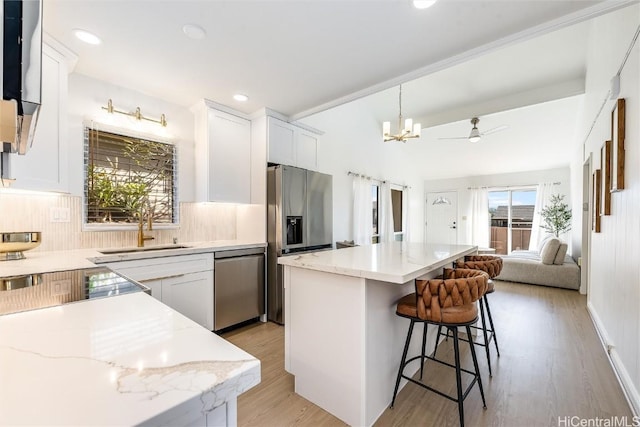 kitchen with tasteful backsplash, stainless steel appliances, sink, white cabinets, and a kitchen island