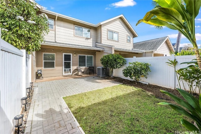 rear view of house with a yard, a fenced backyard, a patio, and central AC unit