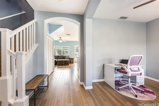 office with arched walkways, visible vents, baseboards, and wood finished floors