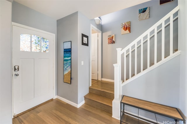 foyer entrance with baseboards, stairway, and wood finished floors