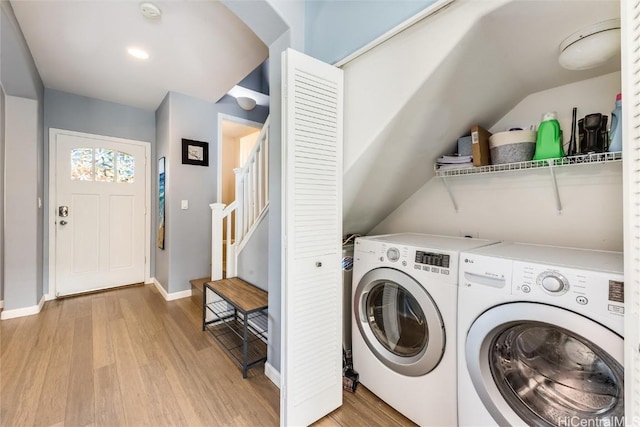 clothes washing area featuring light wood-style floors, laundry area, baseboards, and separate washer and dryer