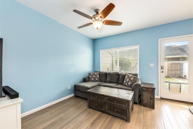 living area featuring light wood-style floors, baseboards, and a ceiling fan