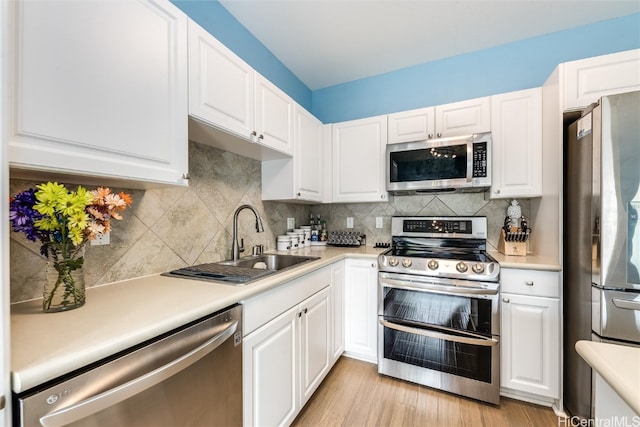 kitchen with stainless steel appliances, a sink, light countertops, and white cabinets