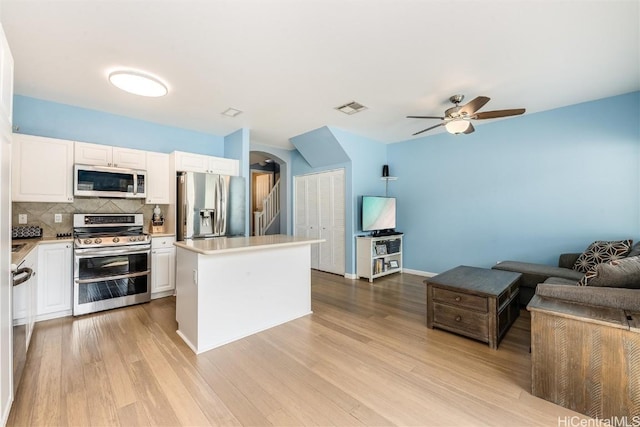 kitchen with appliances with stainless steel finishes, light wood-type flooring, visible vents, and white cabinetry