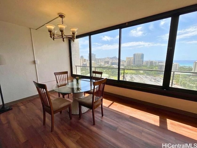 dining room featuring dark wood-type flooring, a notable chandelier, and a water view