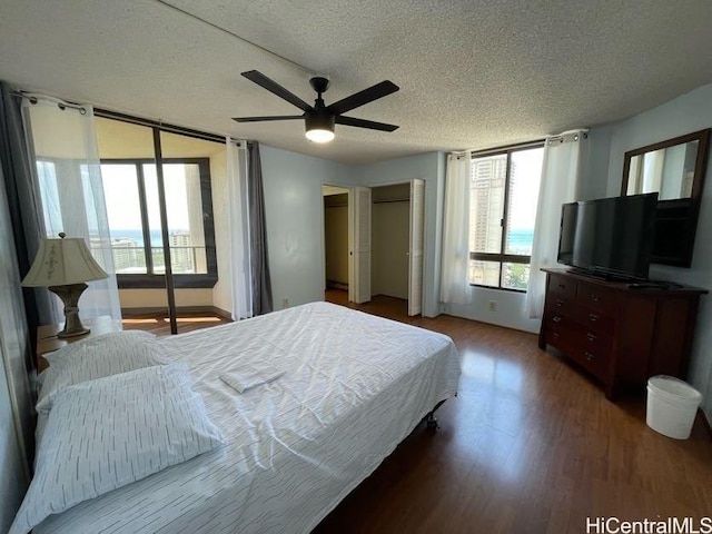 bedroom with hardwood / wood-style flooring, a textured ceiling, and ceiling fan