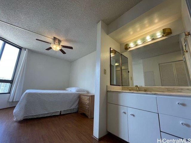 bedroom featuring dark wood-type flooring, a textured ceiling, ceiling fan, and sink