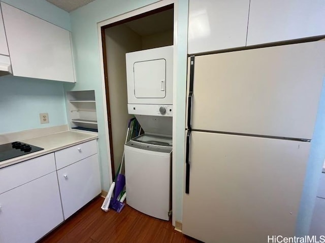 clothes washing area featuring stacked washer and clothes dryer and dark hardwood / wood-style flooring