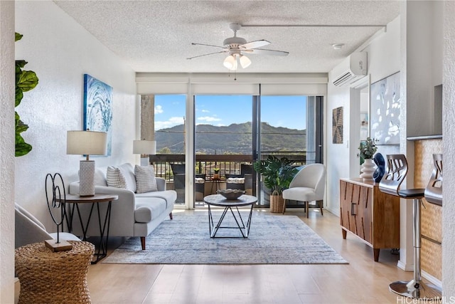 interior space featuring a textured ceiling, a wall mounted air conditioner, a mountain view, and a ceiling fan