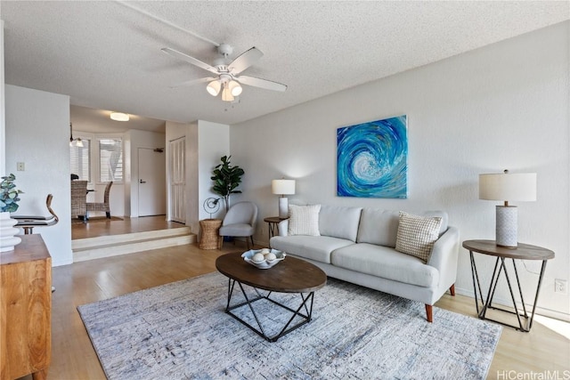 living room featuring a textured ceiling, ceiling fan, and wood finished floors