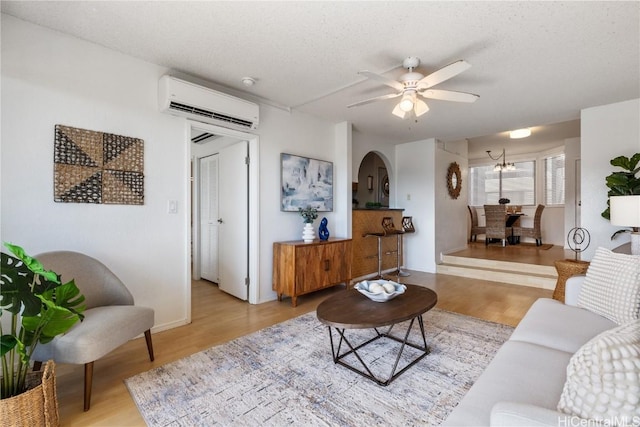 living area with a textured ceiling, an AC wall unit, and wood finished floors