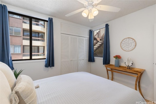 bedroom featuring a textured ceiling, ceiling fan, and a closet