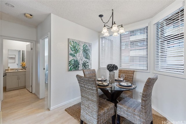 dining room with a chandelier, a wealth of natural light, light wood-style floors, and a textured ceiling