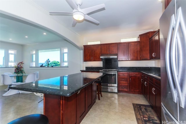 kitchen with under cabinet range hood, stainless steel appliances, a kitchen island, dark brown cabinets, and a kitchen bar