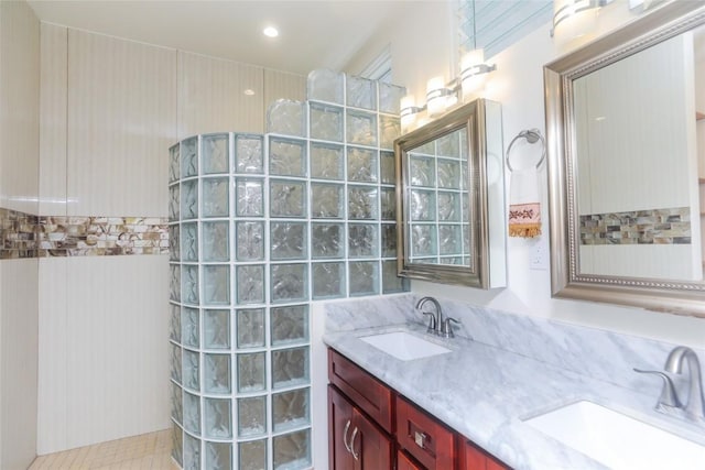 bathroom featuring double vanity, a sink, and a walk in shower