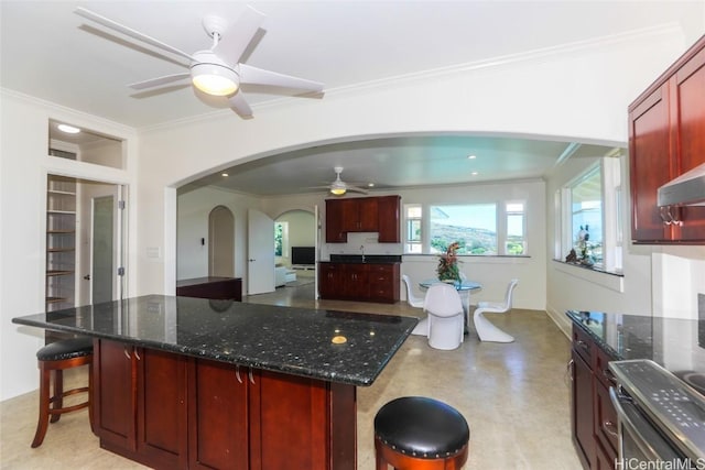 kitchen featuring arched walkways, range, dark brown cabinets, and ornamental molding