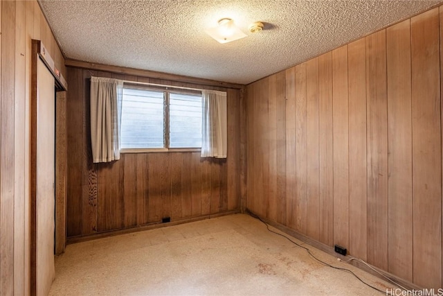 unfurnished room featuring a textured ceiling and wooden walls