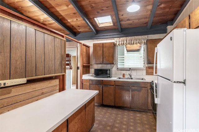 kitchen featuring a skylight, sink, wooden ceiling, beamed ceiling, and white refrigerator