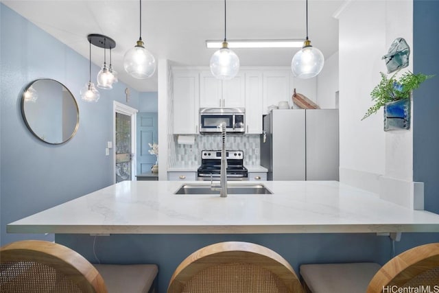 kitchen with decorative light fixtures, a kitchen bar, backsplash, and appliances with stainless steel finishes