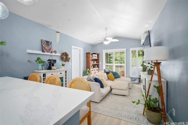 living room featuring light hardwood / wood-style floors, vaulted ceiling, and ceiling fan