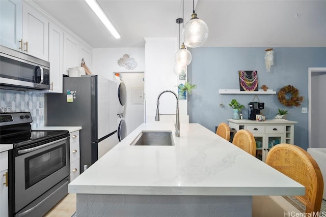 kitchen with pendant lighting, a center island with sink, white cabinets, sink, and stainless steel appliances