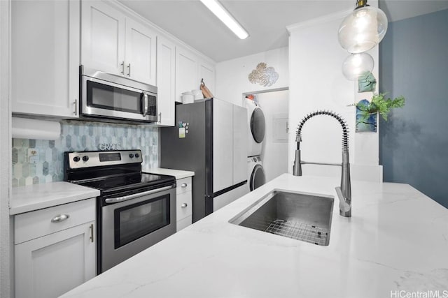 kitchen with stacked washer / dryer, white cabinetry, sink, and appliances with stainless steel finishes