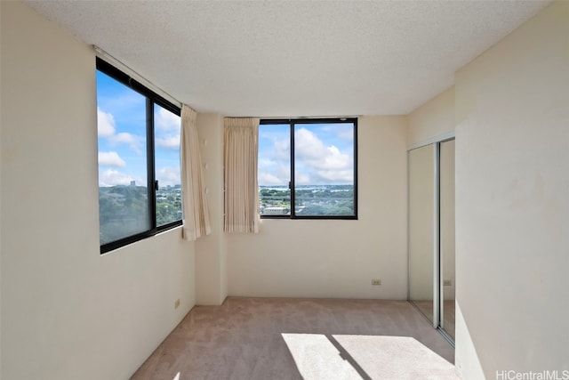 carpeted empty room featuring a wealth of natural light, expansive windows, and a textured ceiling