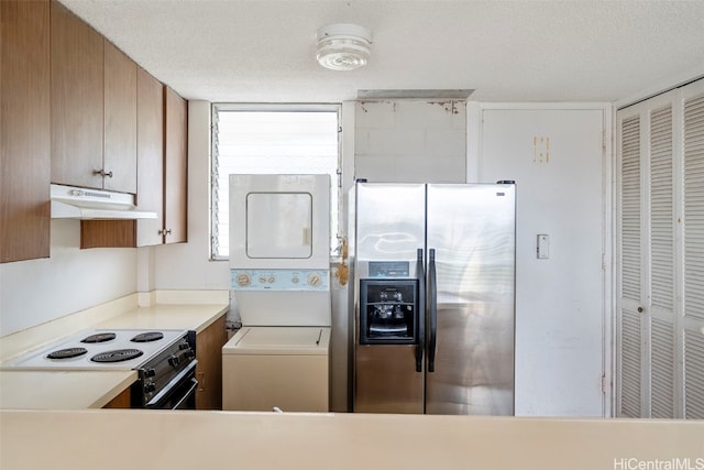 kitchen featuring black range with electric stovetop, stainless steel fridge, a textured ceiling, and stacked washing maching and dryer